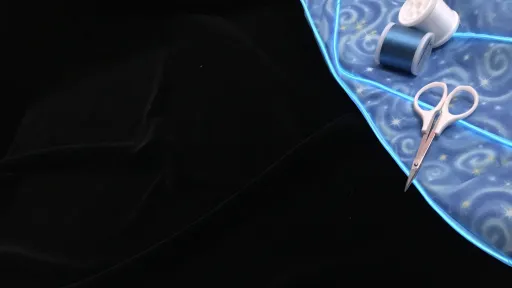Image of fabric with EL wire attached, scissors and thread on a black background